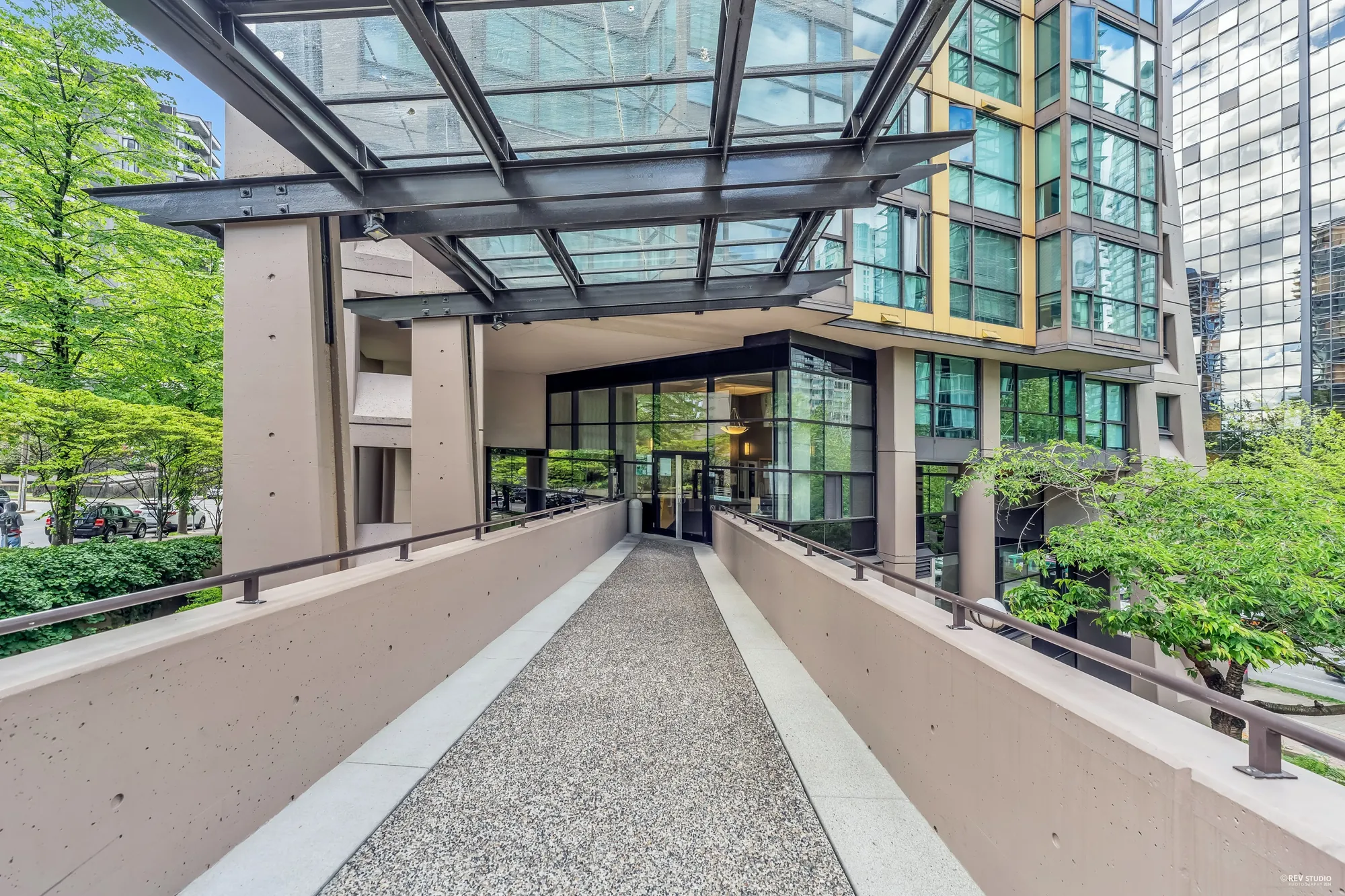 The entrance walk under a glass canopy, the lobby doors at the end