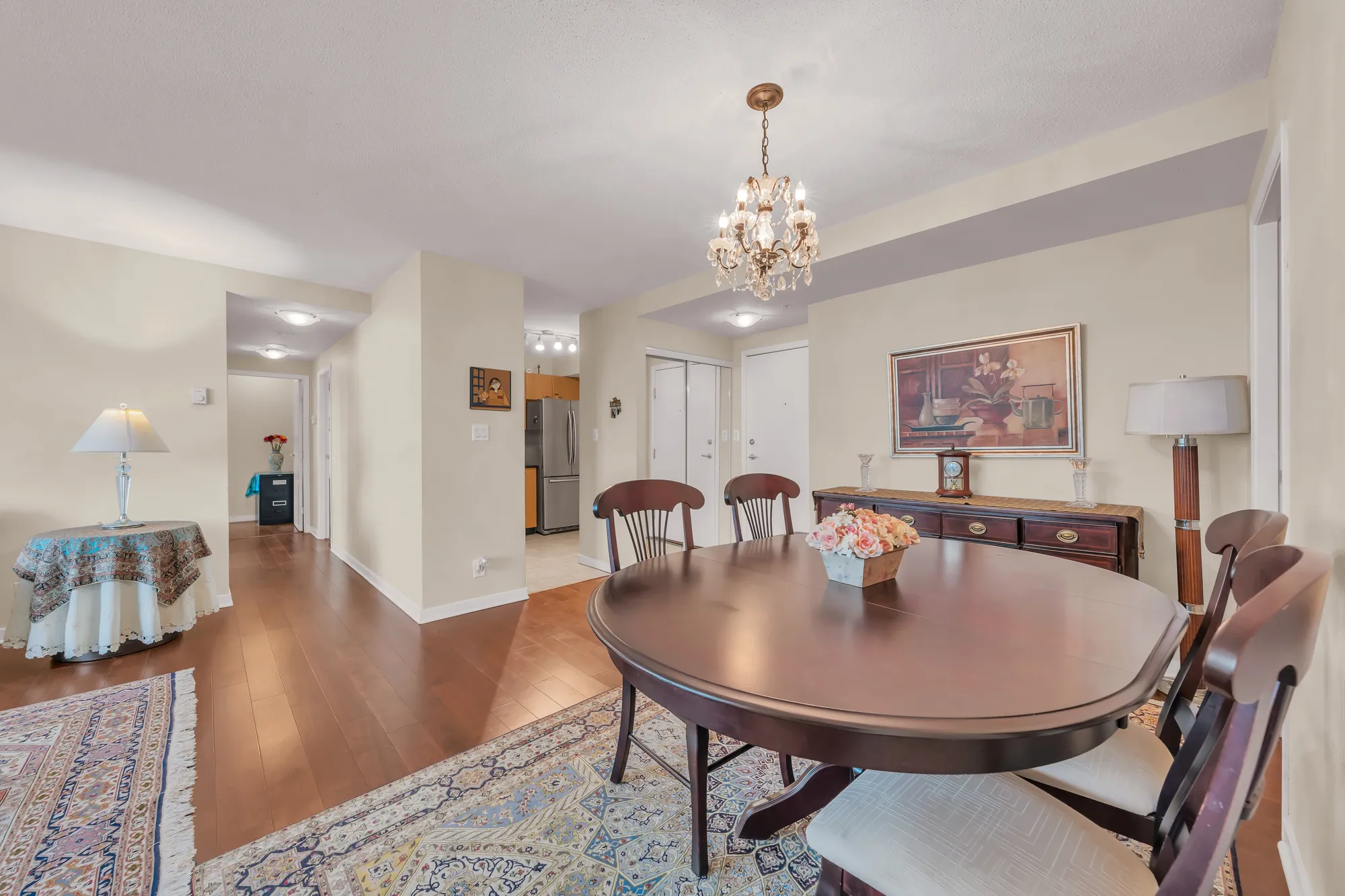The dining table toward the hall and the kitchen, a lamp and a sideboard, hardwood floors