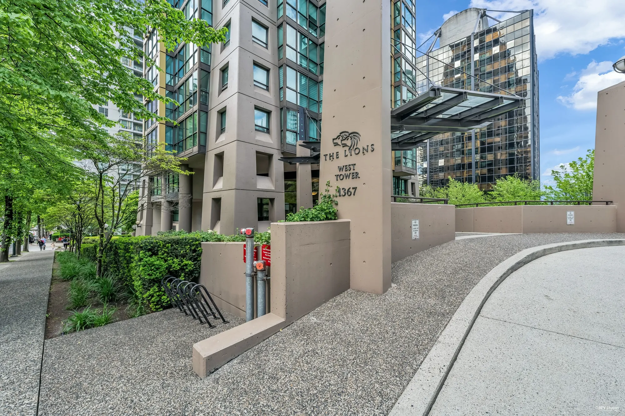 The entrance walk and a stone sign for The Lions West Tower, planting along the path